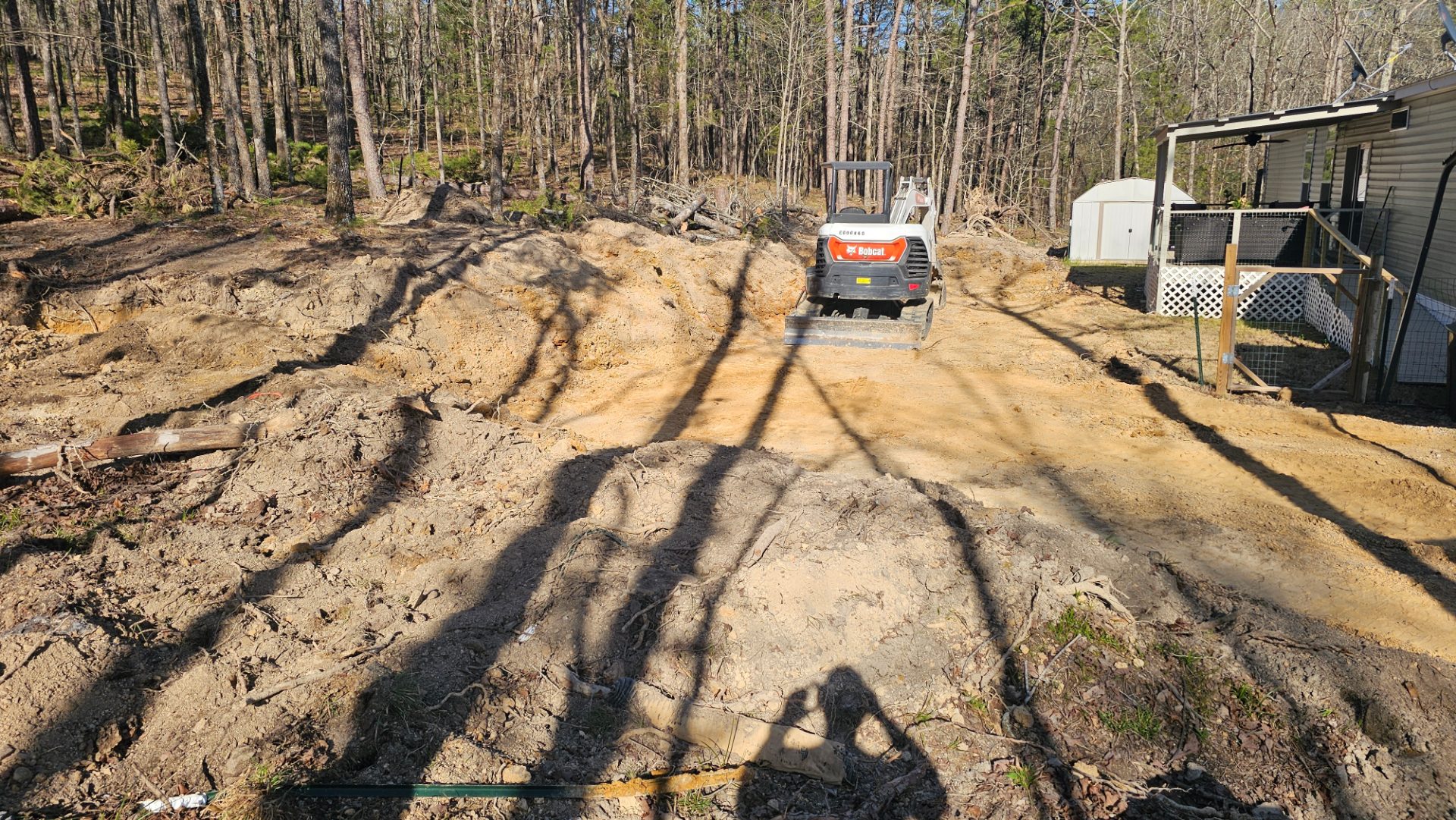 Excavator cutting a building pad beside a home