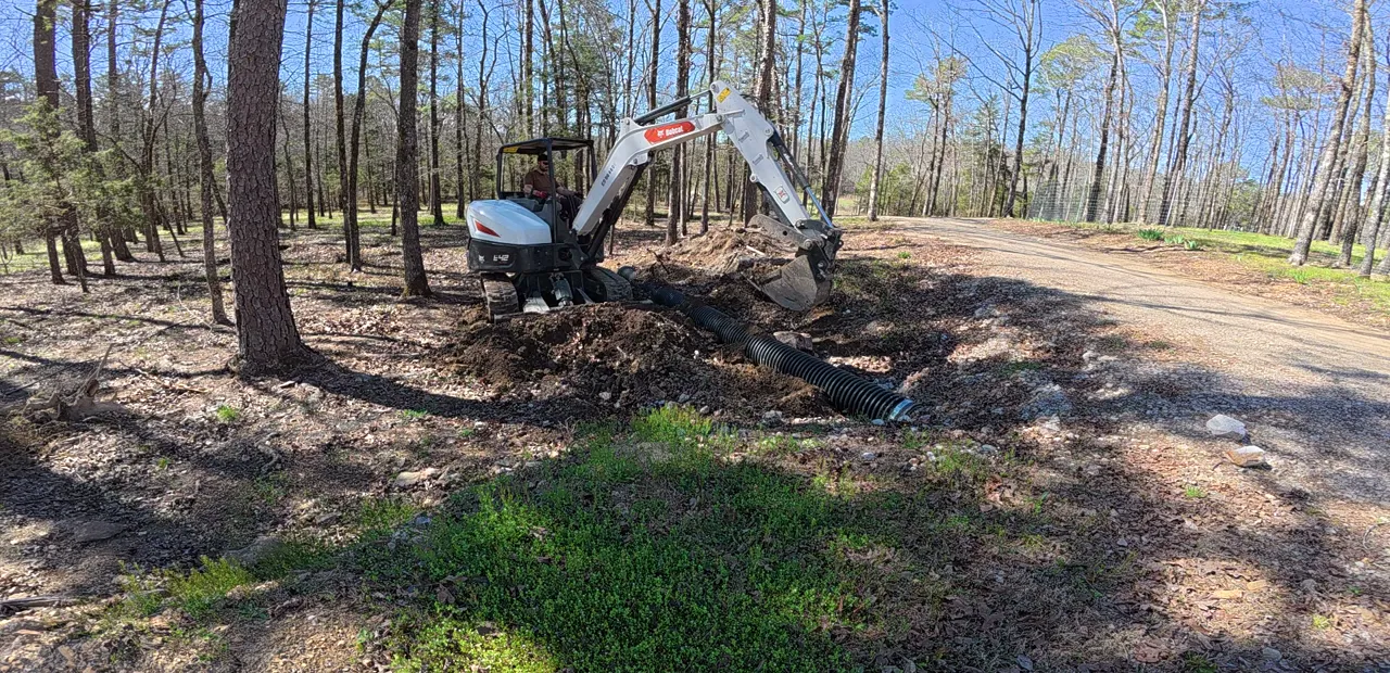 Mini-excavator backfilling around a new culvert pipe