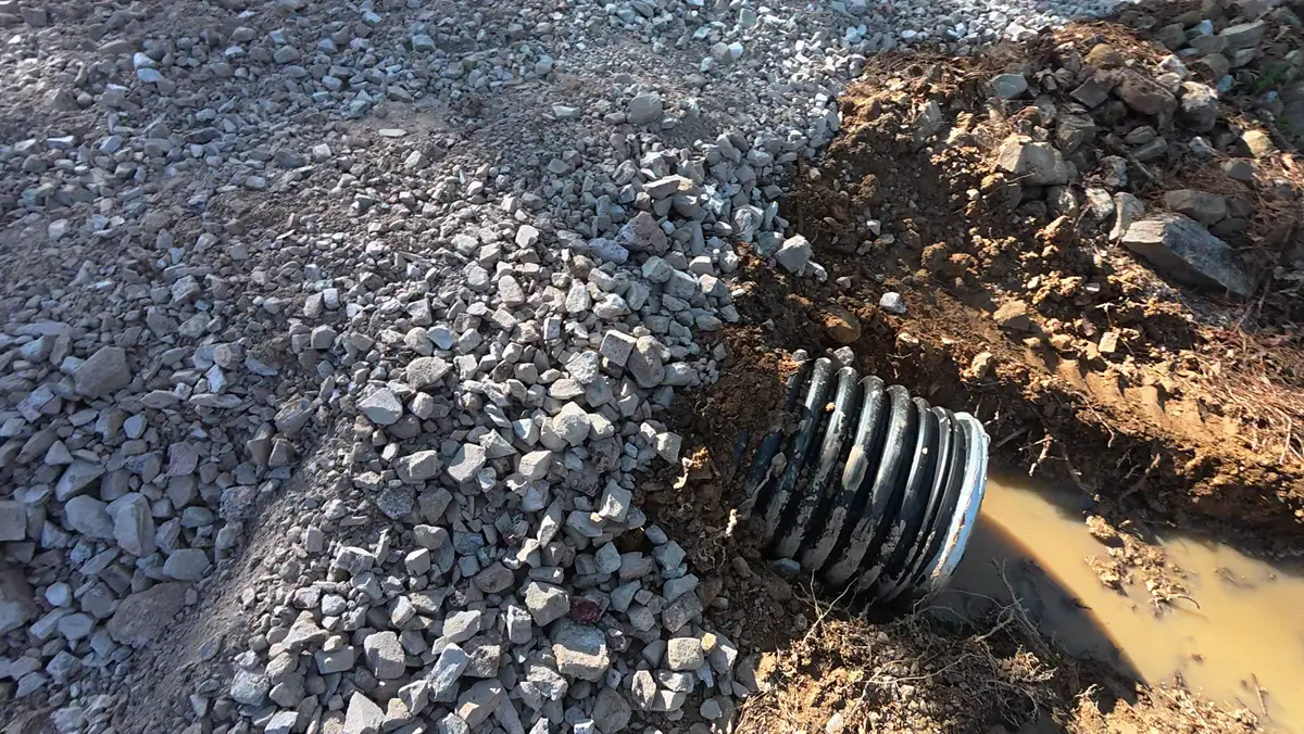 Culvert pipe end set in a trench with crushed stone