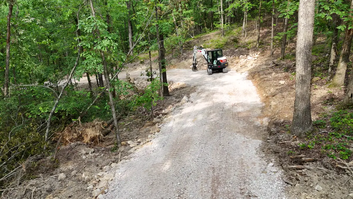 Crushed stone placed on a new drive up a wooded hillside