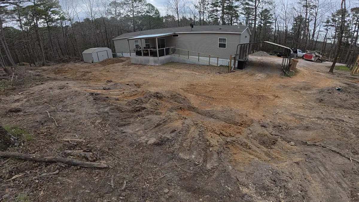 Cleared and graded lot beside a home, shed, and carport
